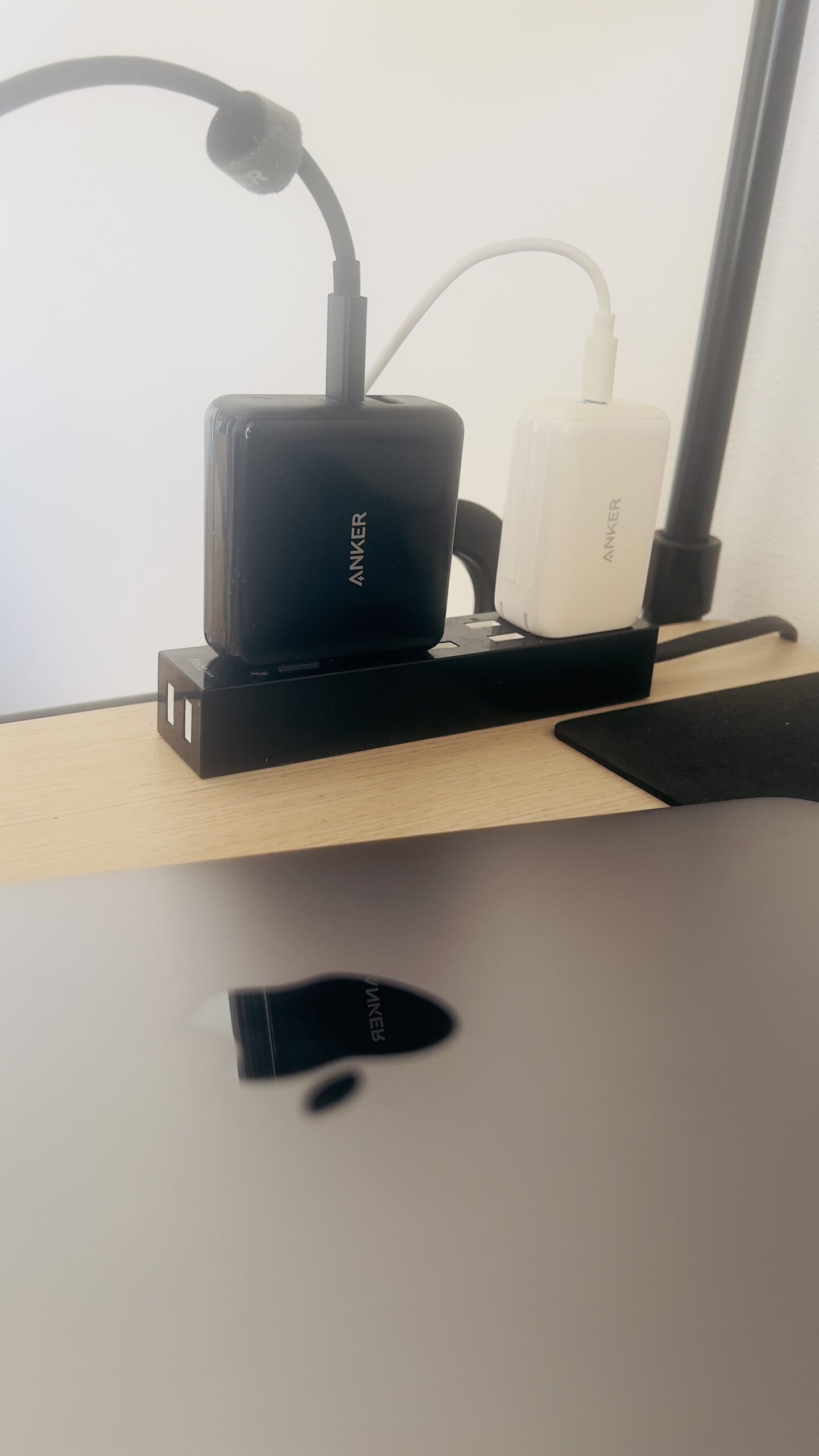 デスク上の電源タップに並ぶAnker製USB急速充電器（黒と白）とMacBook